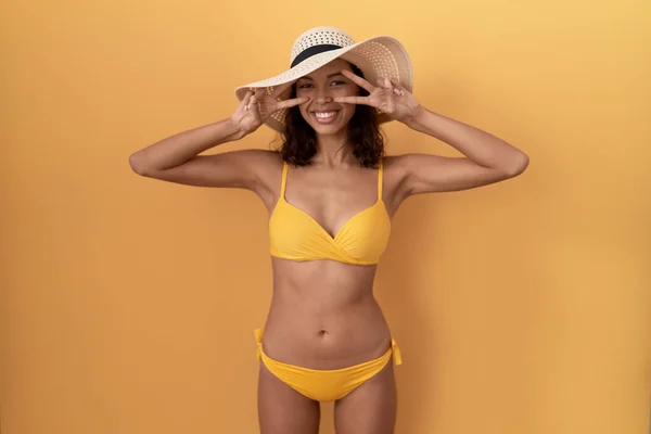 Young Hispanic Woman Wearing Bikini Summer Hat Doing Peace Symbol — Zdjęcie stockowe