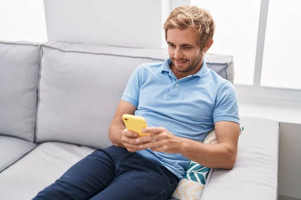 Jovem Usando Smartphone Sentado Sofá Casa — Fotografia de Stock