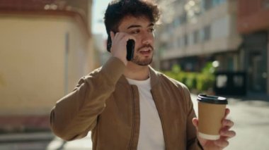 Genç İspanyol adam akıllı telefonda konuşuyor. Sokakta kahve içiyor.