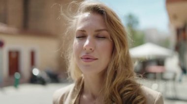 Sokakta kendine güvenen genç sarışın kadın gülümsüyor