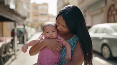 Hispanik aile sokakta öpüşürken birbirlerine sarılıyorlar.