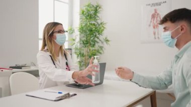Young couple doctor and patient having medical consultation using sanitizer gel hands at clinic