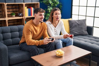 Genç adam ve kadın çift evdeki kanepede oturup oyun oynuyorlar.
