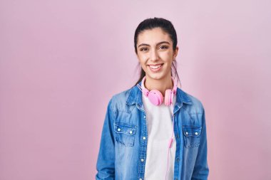 Pembe arka planda mutlu ve havalı bir gülümsemeyle duran genç ve güzel bir kadın. şanslı kişi. 