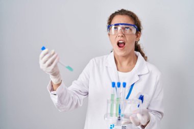 Young caucasian scientist woman working with laboratory samples angry and mad screaming frustrated and furious, shouting with anger looking up. 