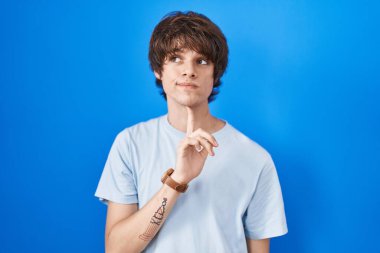 Latin kökenli genç bir adam mavi arka planda durup parmak çenesinde şüpheye yoğunlaşmıştı. 