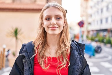 Sokakta kendine güvenen genç sarışın kadın gülümsüyor