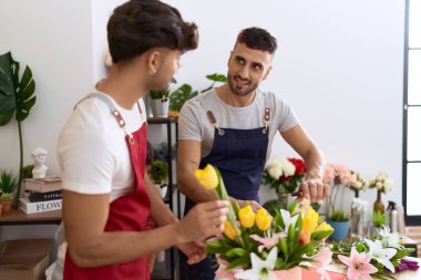 Two hispanic men florists smiling confident make bouquet of flowers at flower shop