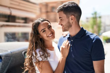 Young hispanic couple smiling confident hugging each other at street