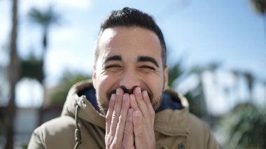 Young hispanic man standing with surprise expression at park