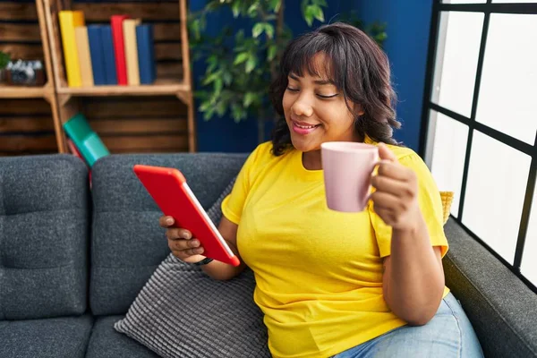 Young Beautiful Latin Woman Using Touchpad Drinking Coffee Sitting Sofa — Stockfoto
