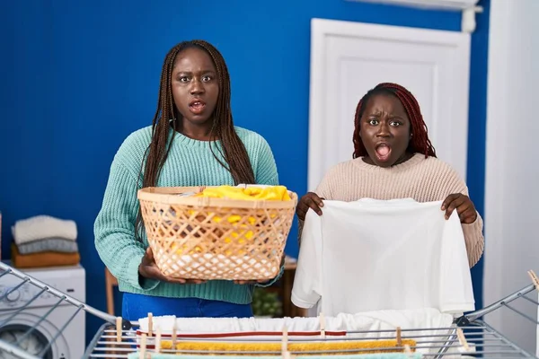 Две Африканки Вешающие Одежду Бельевой Верёвке Шокирующем Лице Смотрят Скептически — стоковое фото