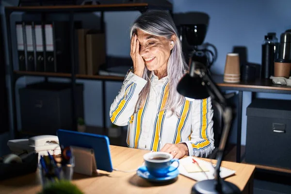 顔に自信満々の笑顔と驚きの感情をカバーし 夜にオフィスで働く白髪の中年女性 — ストック写真