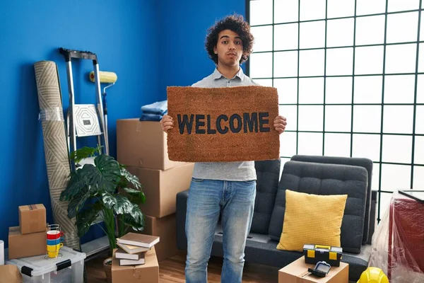 Hispanic Man Curly Hair Holding Welcome Doormat Puffing Cheeks Funny — Stockfoto