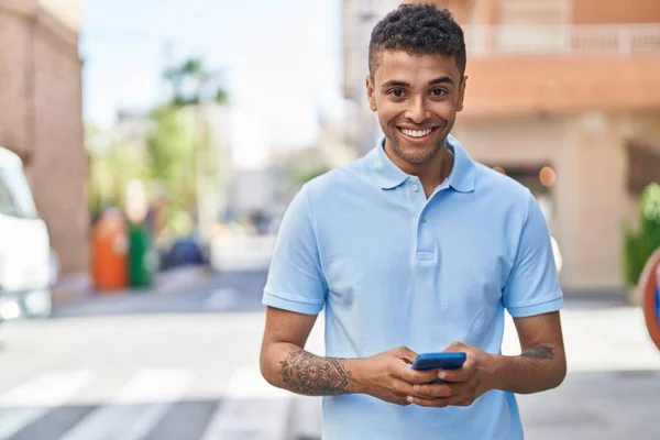 アフリカ系アメリカ人の男が路上でスマートフォンを使って笑顔で — ストック写真
