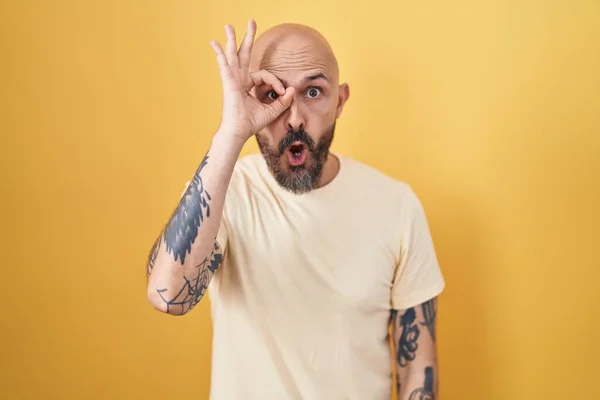 Hispánec Tetováním Stojící Nad Žlutým Pozadím Dělá Pořádku Gesto Šokované — Stock fotografie