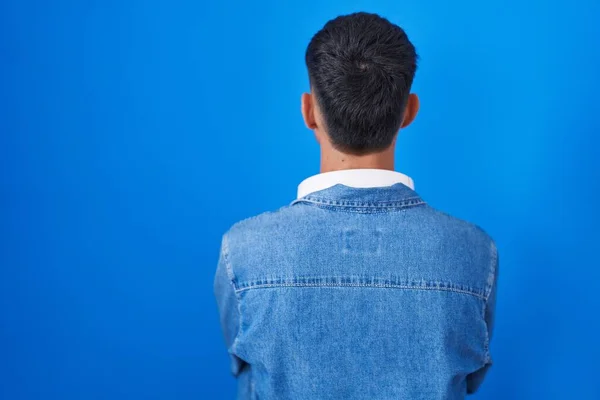 Junger Hispanischer Mann Steht Vor Blauem Hintergrund Und Blickt Rückwärts — Stockfoto