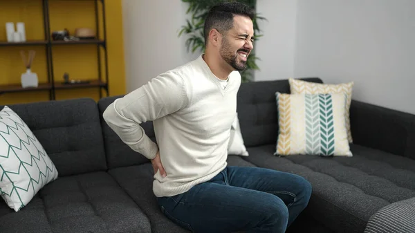 Young Hispanic Man Suffering Backache Sitting Sofa Home — Stockfoto