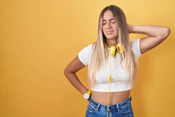 Young Blonde Woman Standing Yellow Background Wearing Headphones Suffering Neck — Stock Fotó