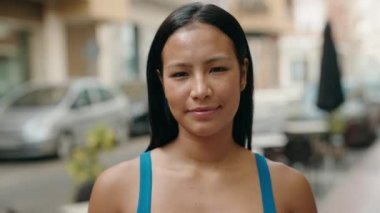 Sokakta kendine güvenen güzel Latin kadın gülümsüyor.