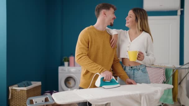 Young Couple Drinking Coffee Ironing Clothes Laundry Room — Vídeos de Stock