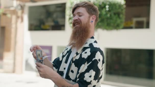 Genç Kızıl Saçlı Adam Gülümsüyor Sokakta Dolarları Sayıyor — Stok video