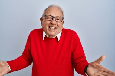 Senior man with grey hair standing over isolated background smiling cheerful with open arms as friendly welcome, positive and confident greetings 