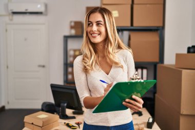 Genç sarışın kadın ecommerce iş işçisi ofisteki panoya yazıyor.