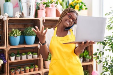 Çiçekçide bilgisayarla konuşan Afrikalı Amerikalı çiçekçi kadın.