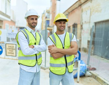 Two hispanic men architects smiling confident standing with arms crossed gesture at street