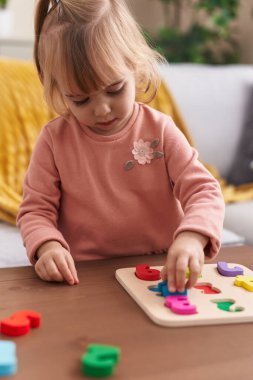 Adorable blonde girl playing maths puzzle game standing at home