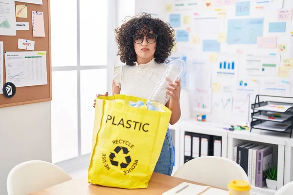 事務所でプラスチックボトルでリサイクルバッグを保持若い中東の女性は懐疑的で緊張し 問題のために動揺を眉をひそめて 否定的な人 — ストック写真