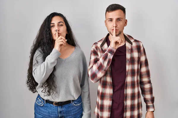 年轻的一对惊慌失措的夫妇站在白色的背景上 要求安静 手指放在嘴唇上 沉默和秘密概念 — 图库照片