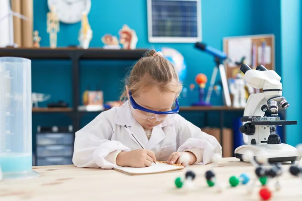 Adorable Blonde Girl Student Using Microscope Writing Notebook Laboratory Classroom — Stok fotoğraf