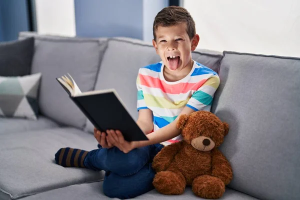 Jovem Caucasiano Criança Sentado Sofá Lendo Livro Furando Língua Para — Fotografia de Stock