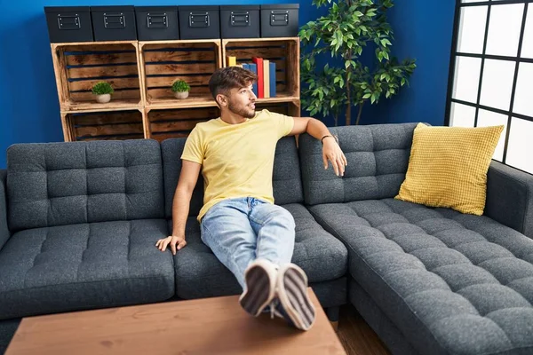 Young arab man smiling confident sitting on sofa at home