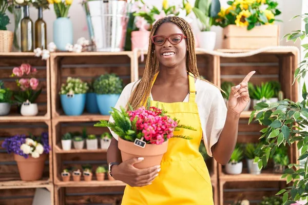 Mujer Afroamericana Con Cabello Trenzado Trabajando Floristería Sosteniendo Planta Sonriendo — Foto de Stock