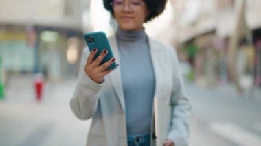 Afro-Amerikalı kadın sokakta akıllı telefon kullanarak kendine güveniyor.