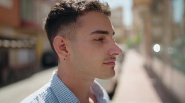 Young hispanic man smiling confident looking to the side at street