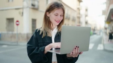 Young caucasian woman smiling confident using laptop at street