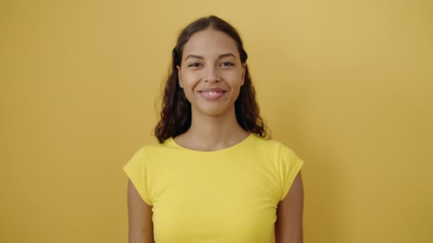 若いアフリカ系アメリカ人女性が自信を持って立って笑って孤立した黄色の背景 — ストック動画