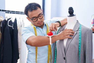 Young chinese man tailor measuring jacket at tailor shop