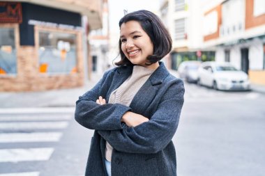 Young woman standing with arms crossed gesture looking to the side at street