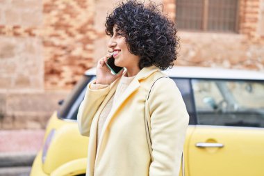 Young middle east woman excutive smiling confident talking on the smartphone at street