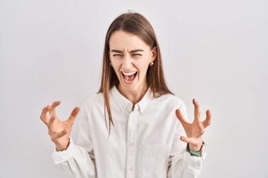 Young caucasian woman standing over isolated background crazy and mad shouting and yelling with aggressive expression and arms raised. frustration concept. 