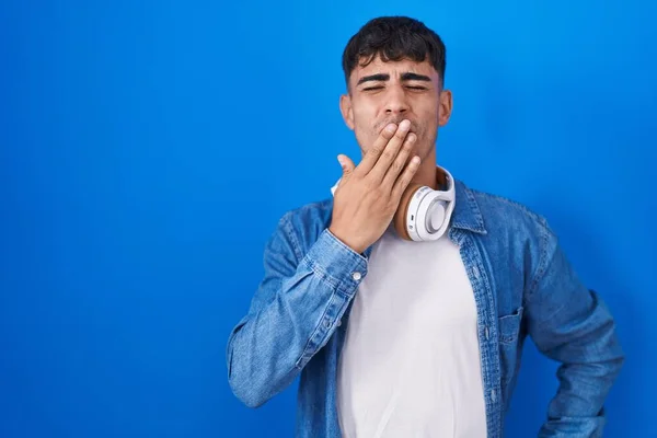 Молодой Латиноамериканец Стоящий Синем Фоне Устал Зевать Прикрывая Рот Рукой — стоковое фото