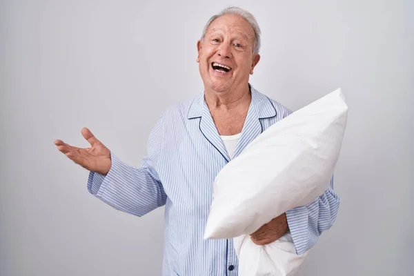 Senior Man Grey Hair Wearing Pijama Hugging Pillow Pointing Aside — Stockfoto