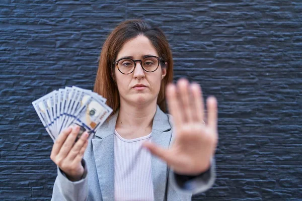 Morena Mulher Segurando Dólares Com Mão Aberta Fazendo Sinal Parada — Fotografia de Stock