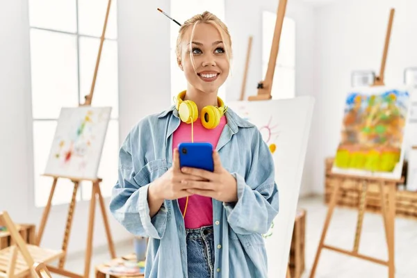 若い白人女性アーティストがアートスタジオでスマートフォンを使って — ストック写真