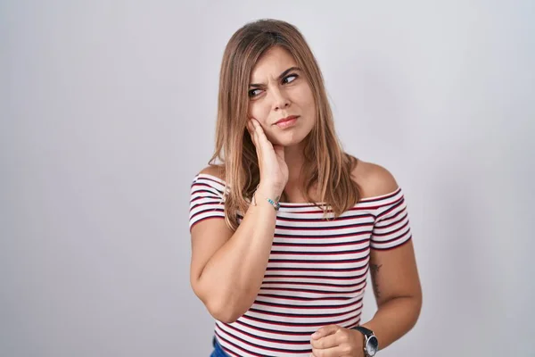 Young hispanic woman standing over isolated background touching mouth with hand with painful expression because of toothache or dental illness on teeth. dentist
